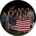 Group image of men and women holding an American flag while smiling