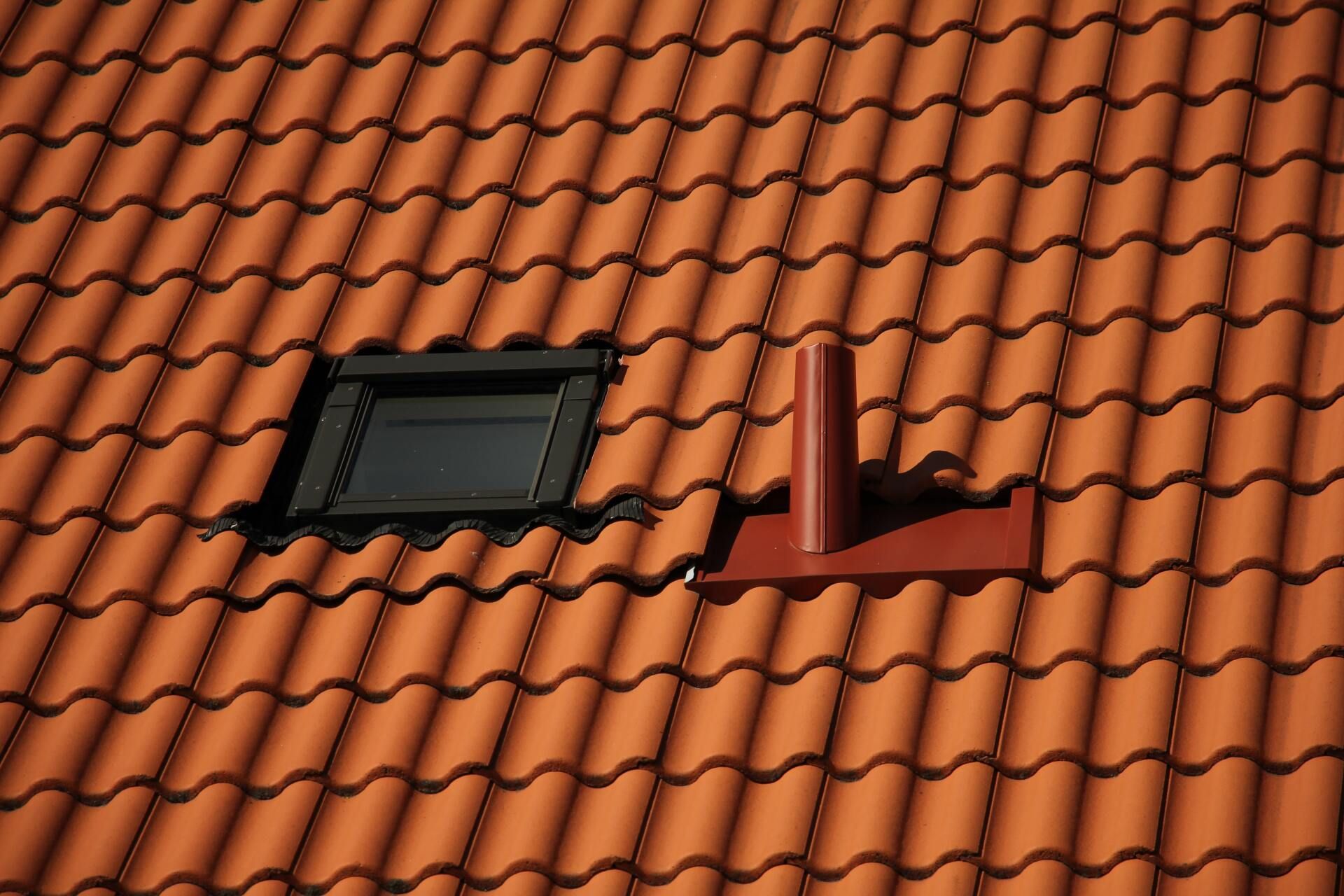 Red tiled roof with a dark skylight and a red vent pipe