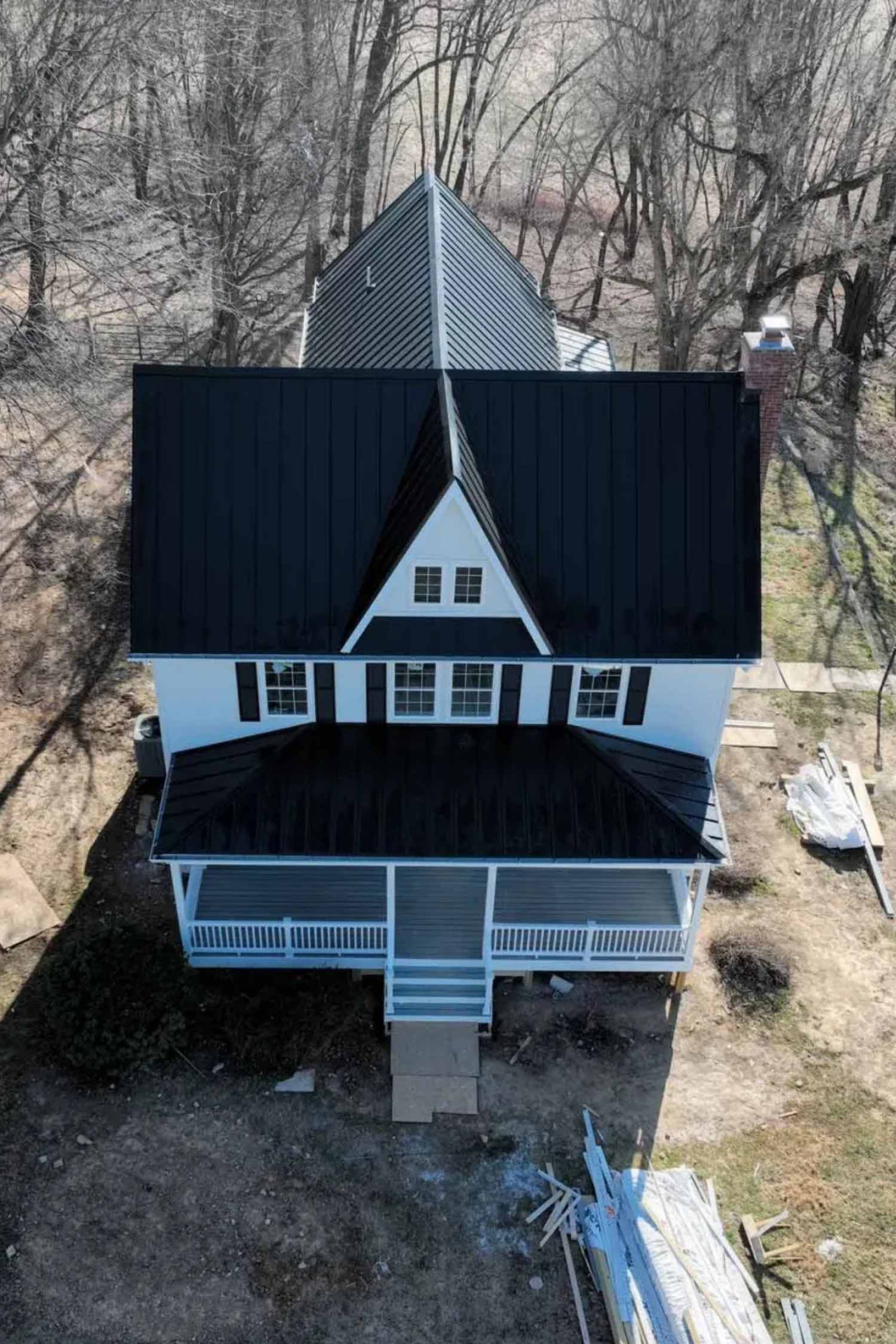 Aerial view of a large white farmhouse with a black metal roof